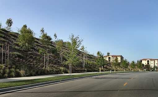 A road with a hill on one side and a building on the other.