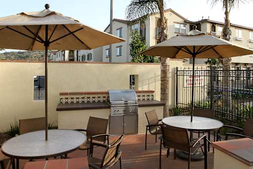 A patio with a table, chairs and umbrellas.