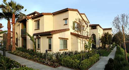 A row of houses with a sidewalk in front.