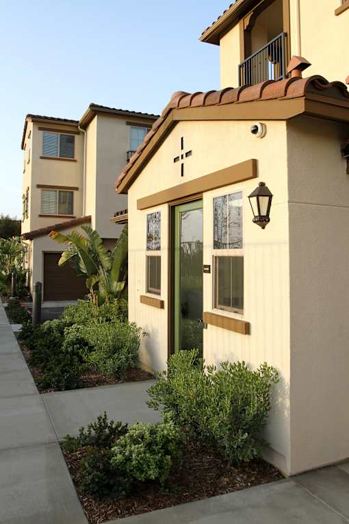 A small house with a brown door and a cross on the front.