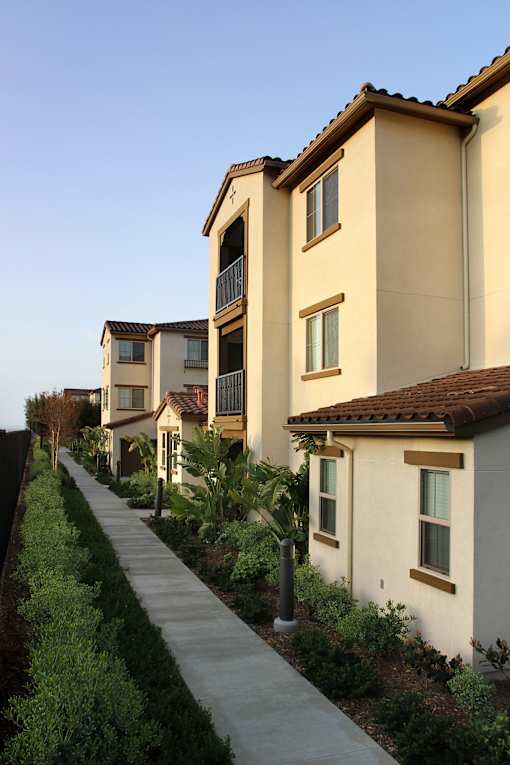 A long row of houses with a sidewalk in between.