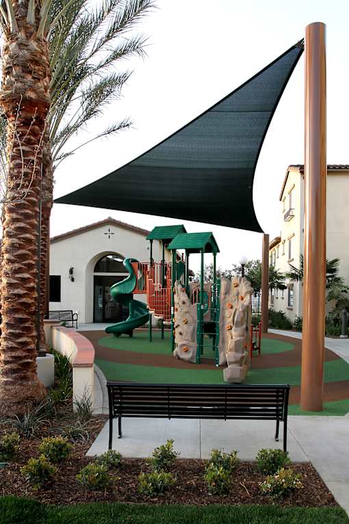 A playground with a green slide and a black bench.