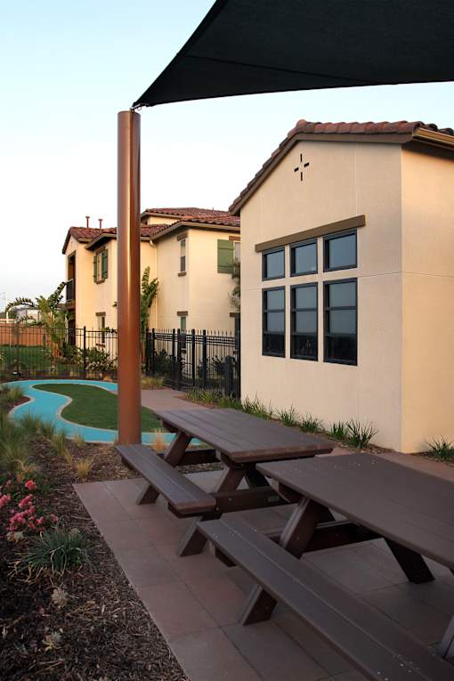 Picnic tables are set up outside of a tan building.