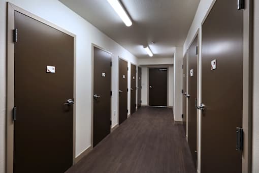 A long hallway with brown doors and wood floors.