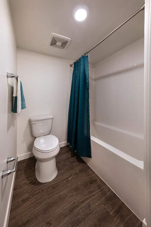 A white toilet with a blue curtain in the background.