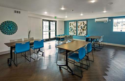 A room with tables and chairs and a blue chair.