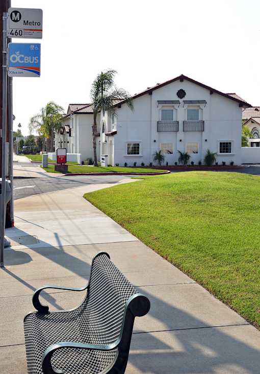 A bench is on a sidewalk in front of a house.