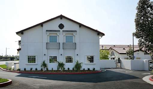 A white building with a black roof and a black gate.