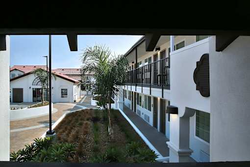 A white building with a black fence and a small garden in front.