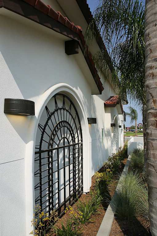 A white house with a black gate and a palm tree in front.