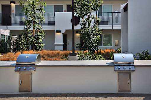 Two grills are on a wall outside a building.