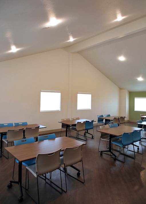 A classroom with tables and chairs and windows.