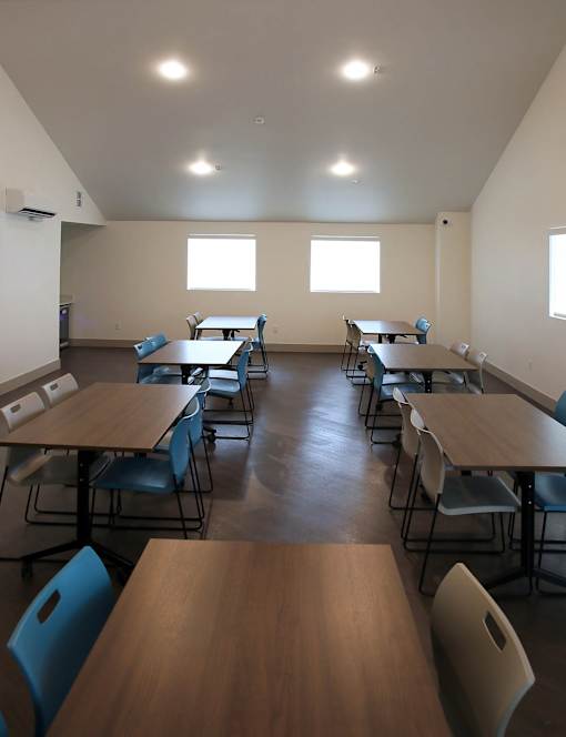 A room with tables and chairs and windows.