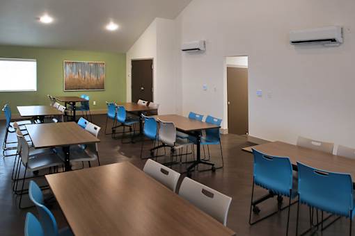 A room with tables and chairs and a painting on the wall.