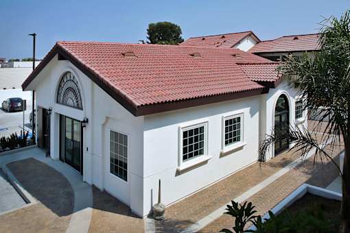 A white house with a red roof and a brown door.