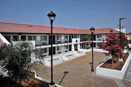 A building with a red roof and white walls with a black lamp post in front.