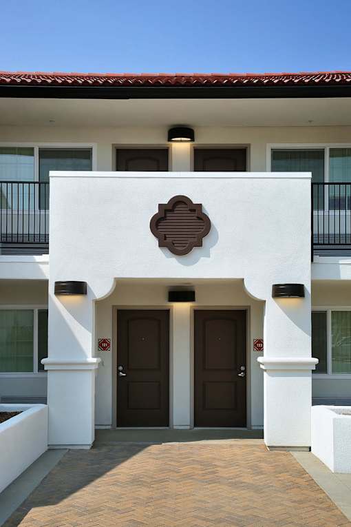 A white building with a brown door and windows.