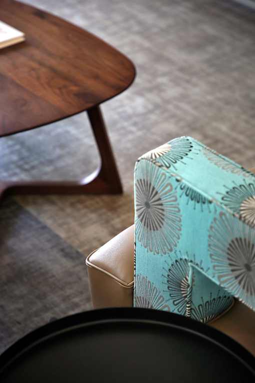 A blue and white patterned cushion sits on a beige chair.