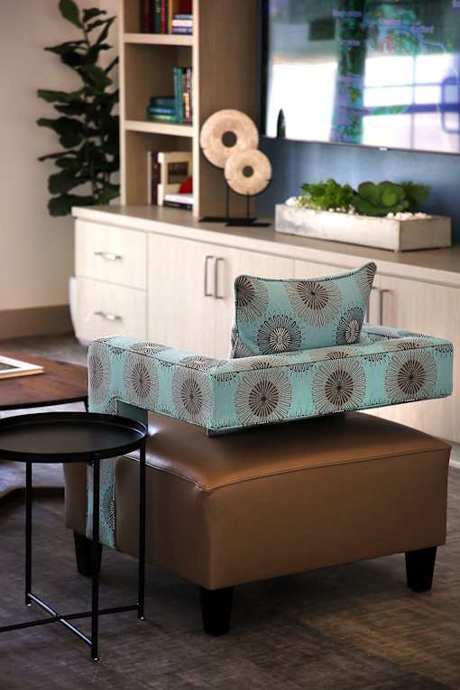 A blue and white patterned chair sits on a brown ottoman.