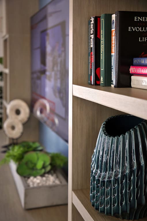 A shelf with books and a green vase.