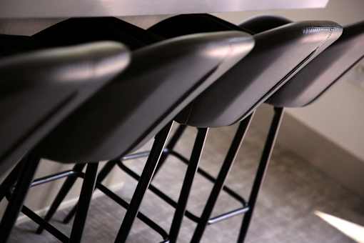A row of black chairs with metal legs and cushioned seats.