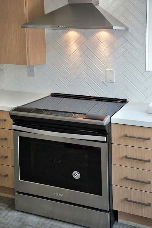 A stainless steel oven with a black top is installed in a kitchen with wooden cabinets.