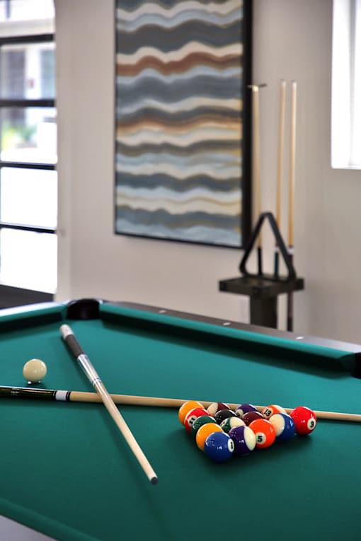 A pool table with a green cloth and a white ball and cue stick on it.
