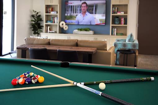 A pool table with a green cloth and a set of pool cues and balls.