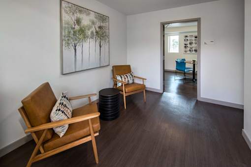 A living room with a brown chair and a painting on the wall.