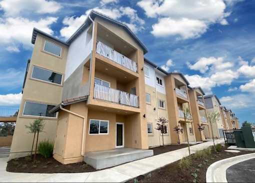 A row of modern apartment buildings with balconies and landscaping.