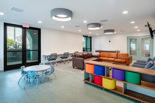 A conference room with a white table and chairs, a couch, and a TV.