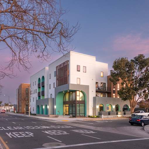 A white building with a green trim is on a street corner.