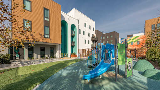 A playground with a blue slide and a green hill.
