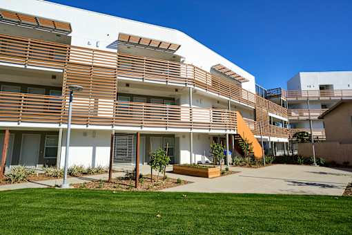A modern building with a white and brown exterior and a green lawn in front.