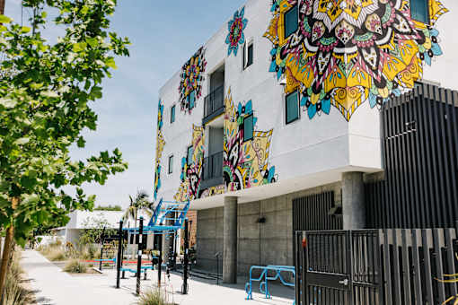 A colorful mural on a building with a playground in front.