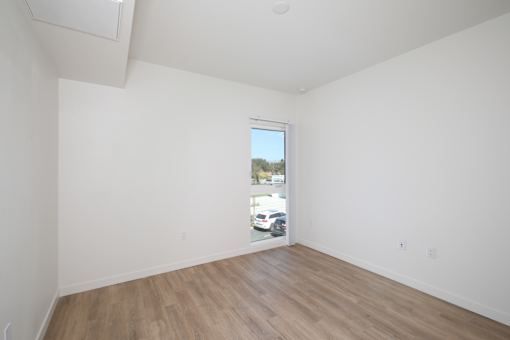 Empty room with a window and wooden floor.
