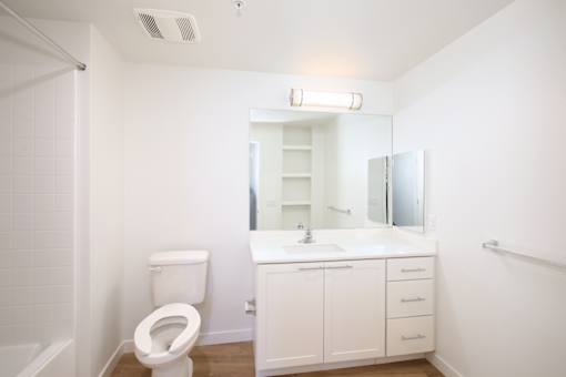 A white bathroom with a toilet, sink, and mirror.