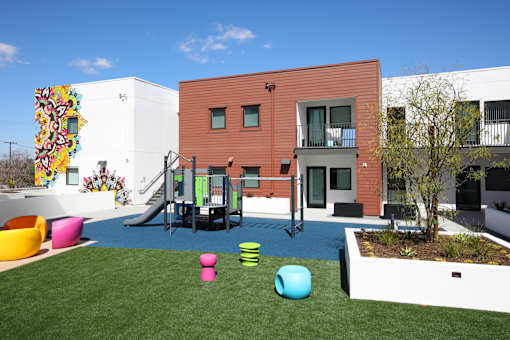 A playground area with a slide and a building in the background.