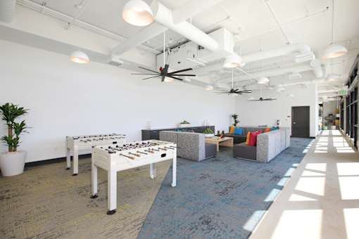 A room with a foosball table and a couch.