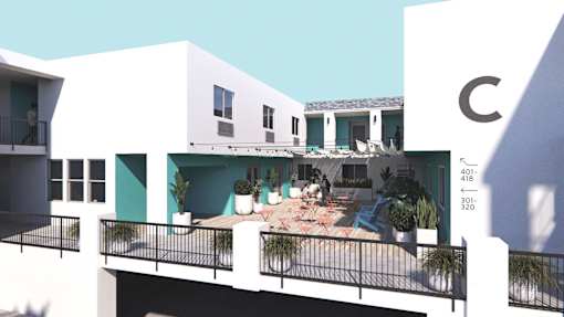 A white building with a balcony and a blue sky in the background.