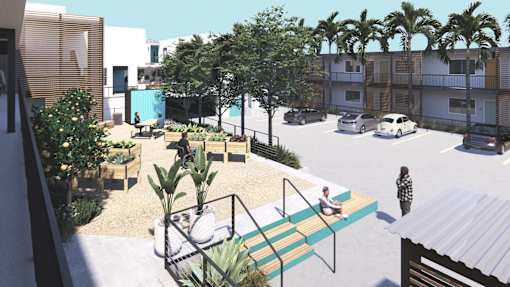 A modern outdoor seating area with a table and chairs surrounded by greenery and a parking lot in the background.