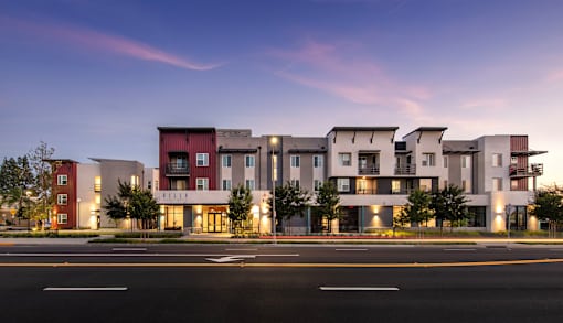 A modern apartment complex is lit up at dusk.