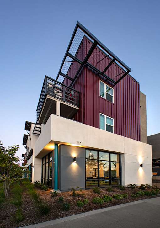A modern house with a red and white exterior and a balcony.