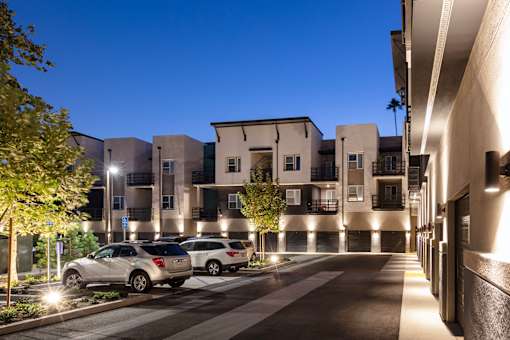 A modern building with cars parked in front at night.