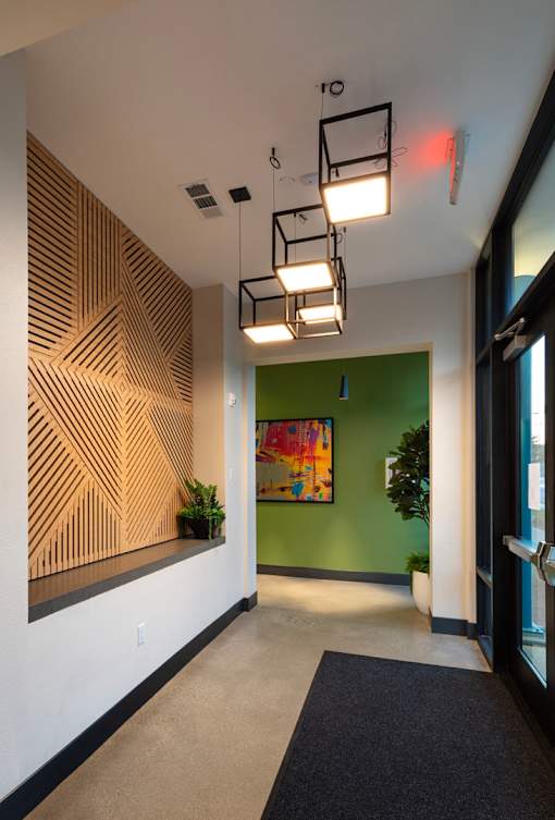 A hallway with a black carpet and a green wall.