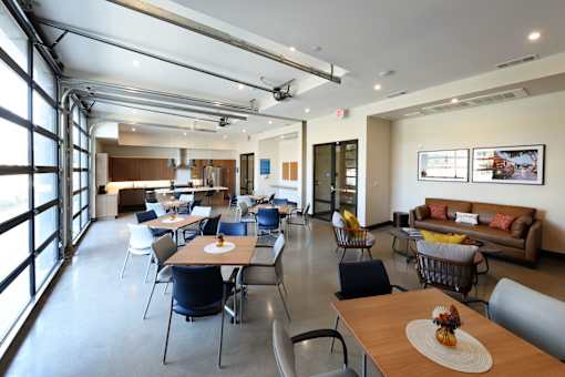 A large room with tables and chairs and a couch.