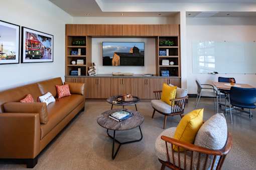 A living room with a brown couch, a coffee table, and a large painting on the wall.