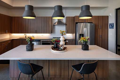 A modern kitchen with a white countertop and dark chairs.
