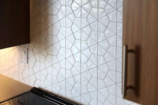 A kitchen with a tile backsplash and a wooden cabinet.