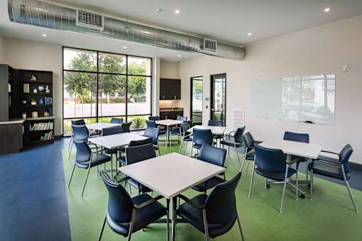 A room with tables and chairs and a whiteboard on the wall.